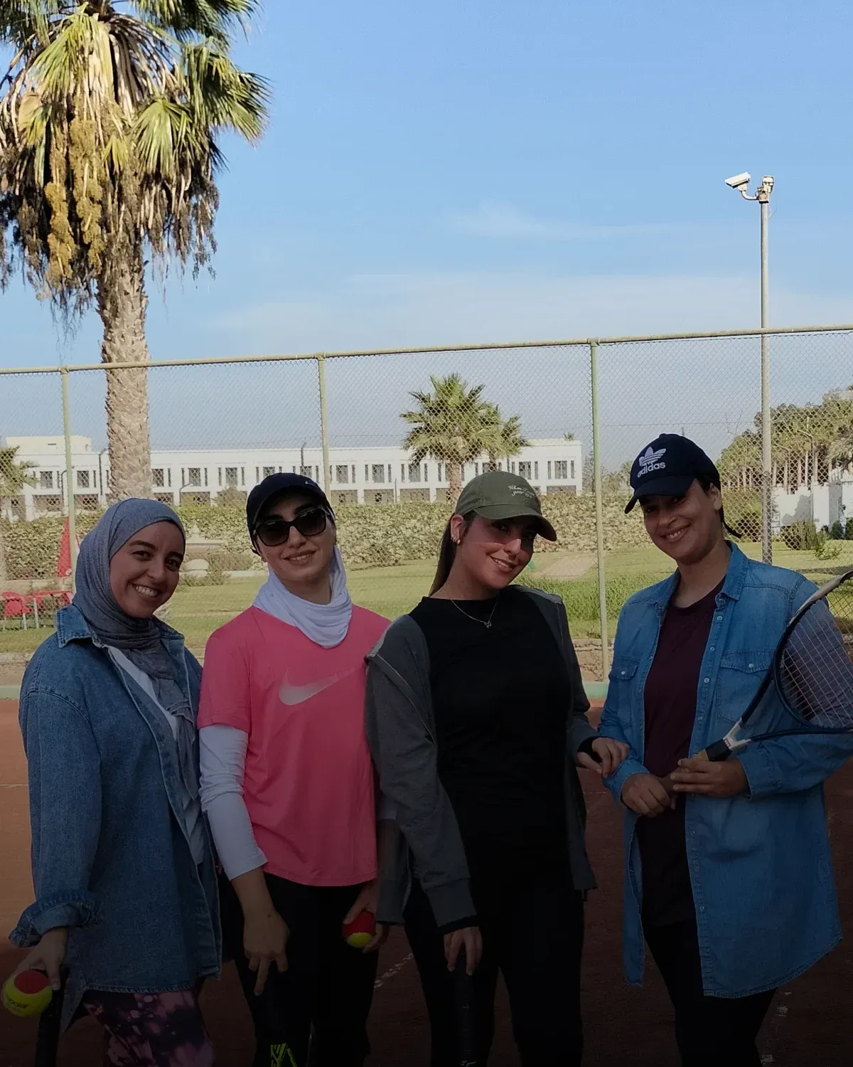 Créneau 100 % femmes : quatre joueuses du club, raquette et balles en main, au bord du court
