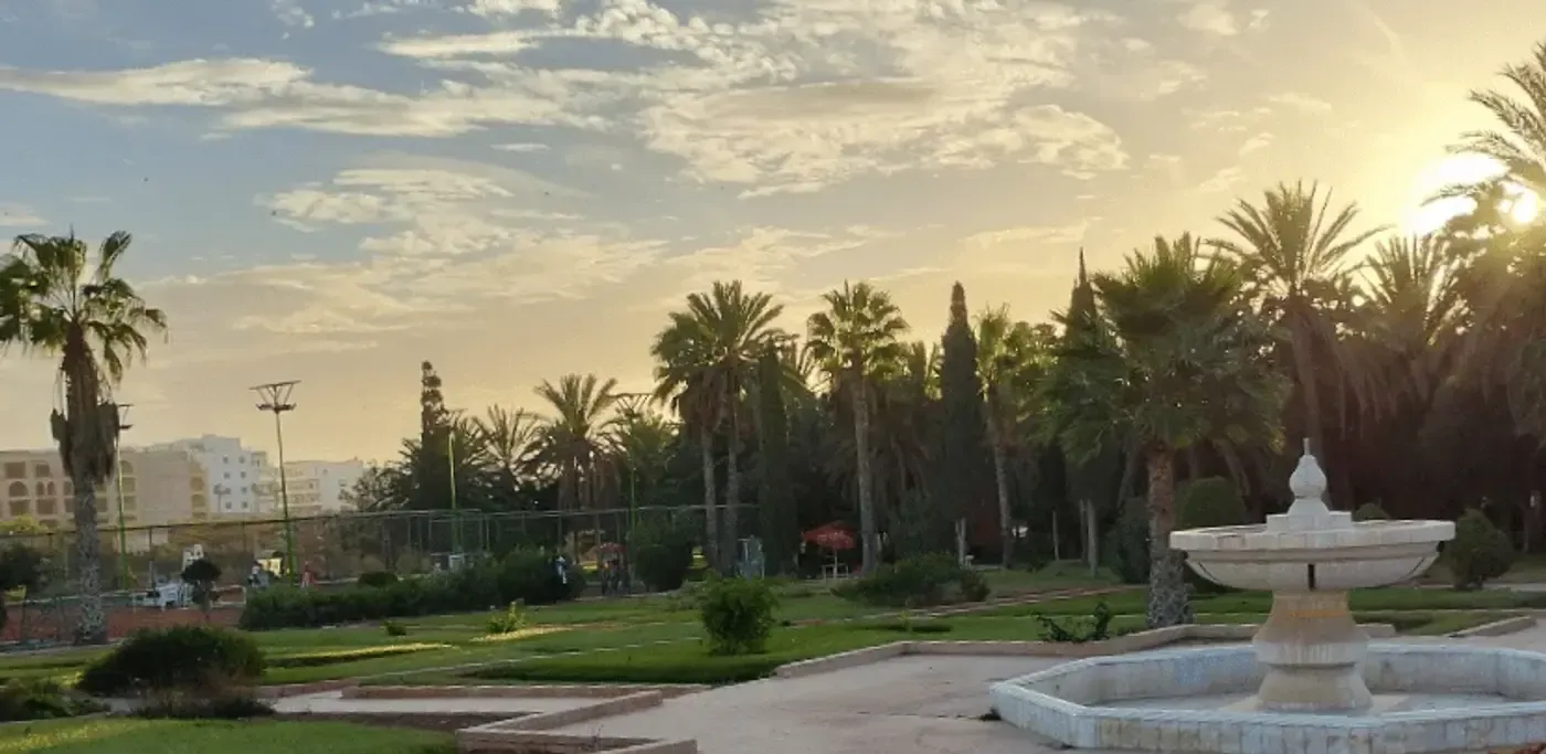 Les jardins et la fontaine du club au coucher du soleil, palmiers en arrière-plan