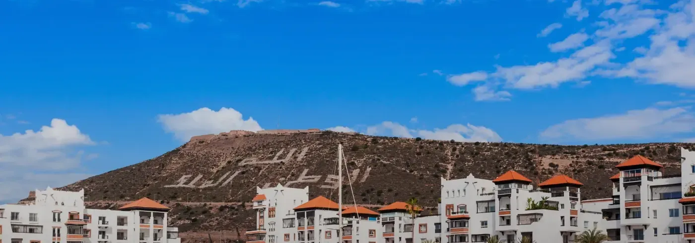 Jouer au tennis sous le soleil d'Agadir : la colline de la kasbah et les toits de la marina, sous un ciel dégagé
