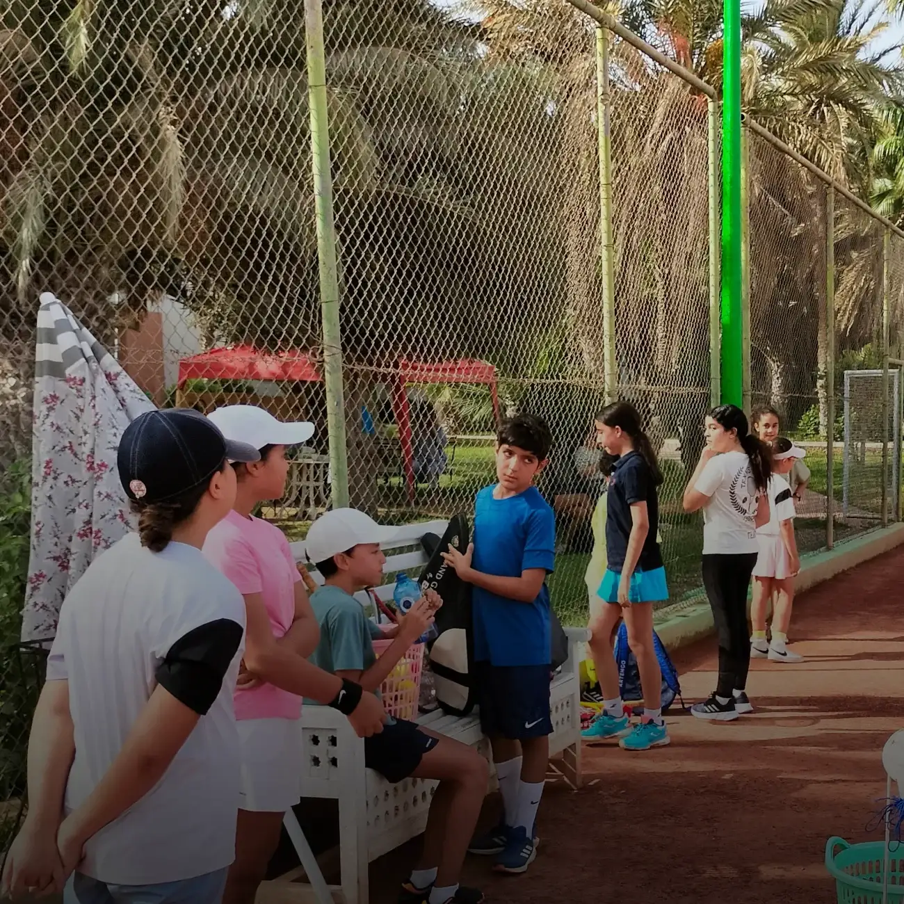Stage tennis jeunes : le groupe rassemblé au bord du court en terre battue du club
