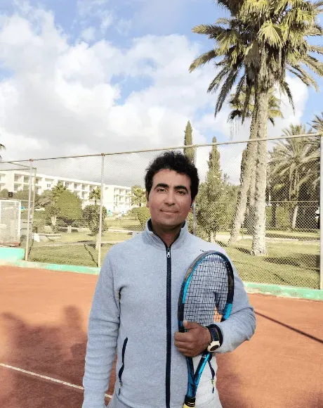 Said Akhabbar, head coach du club, raquette à l’épaule devant un court en terre battue