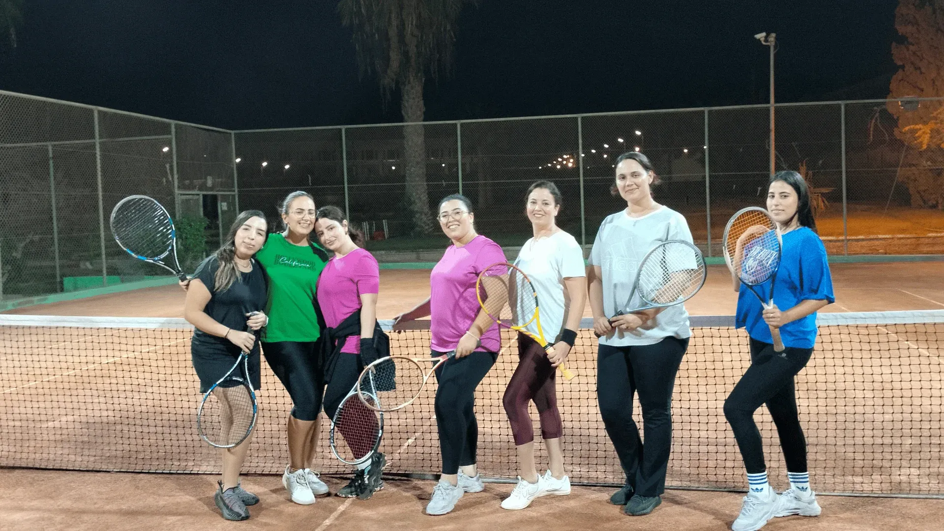 Cours de tennis réservés aux femmes : le groupe des joueuses du club réuni au filet, en soirée
