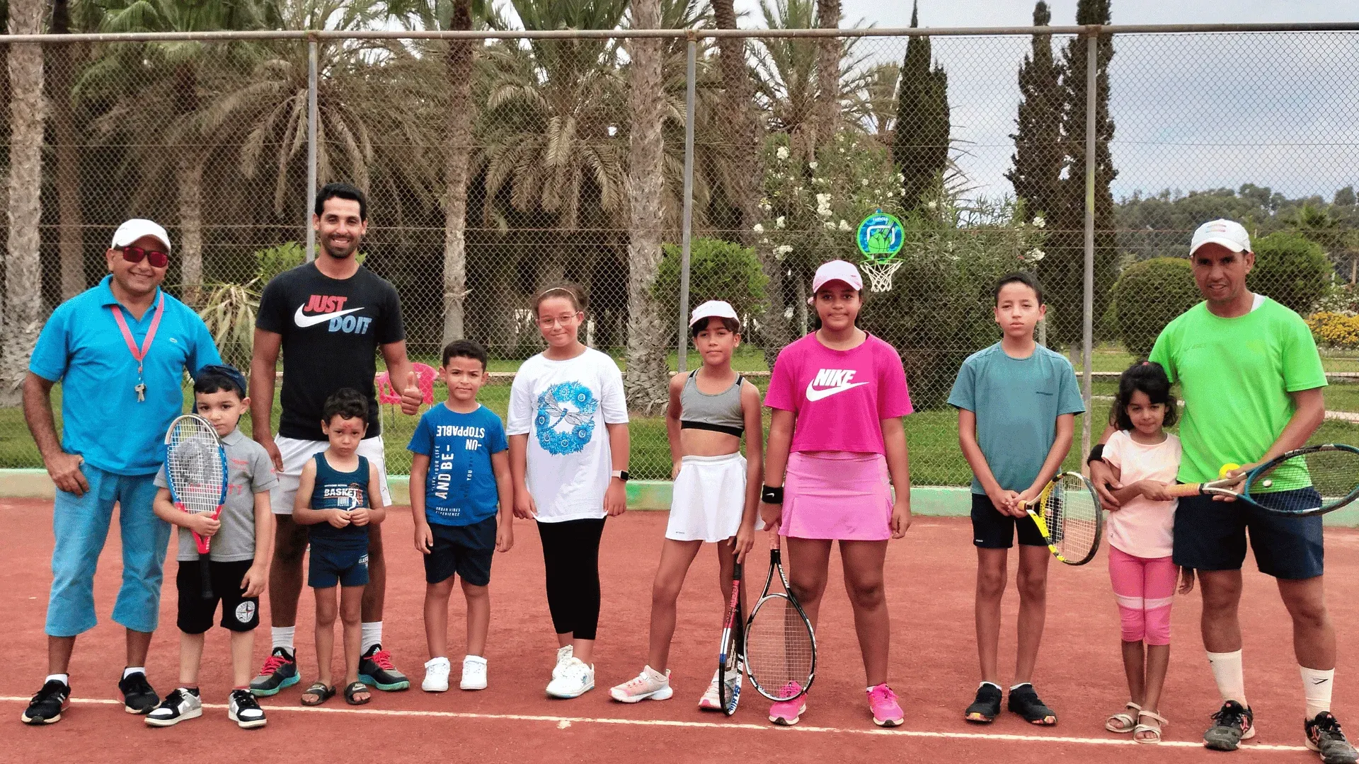 La communauté de l'école de tennis d'Agadir : les jeunes et leurs coachs alignés sur la terre battue