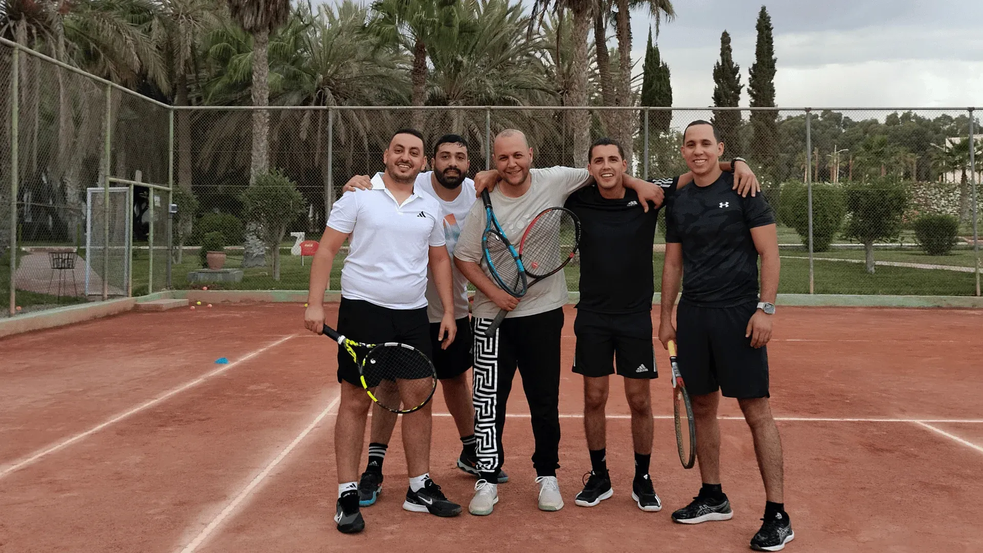École de tennis adultes : cinq joueurs du club réunis raquette à la main sur la terre battue