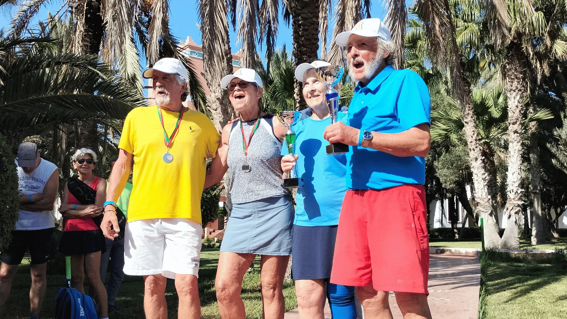 Séjour tennis au club d'Agadir : quatre participants, trophées et médailles en main, sous les palmiers